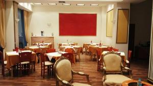 a dining room with tables and chairs and a red painting at Hotel King in Kalabaka