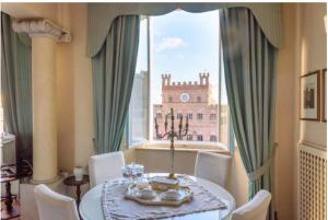 uma sala de jantar com uma mesa e uma grande janela em Palazzo Lenzi em Siena