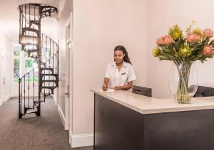 a woman standing at a counter with a vase of flowers at Avondale Boutique Hotel in Durban