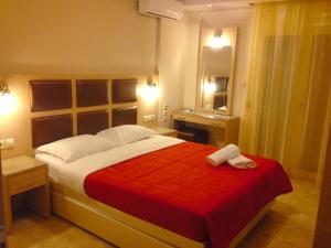 a bedroom with a large bed with a red blanket at Gaia Studios & Apartments in Nea Plagia