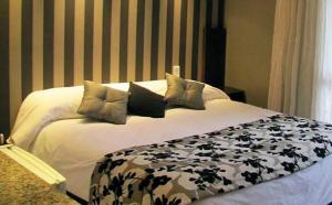 a bed with black and white sheets and pillows at Hotel Sierra de los Padres in Sierra de los Padres
