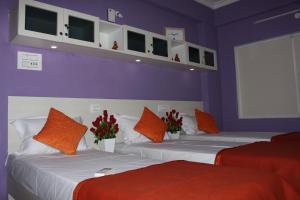 two beds with orange and white pillows in a room at Mahas Inn in Hyderabad