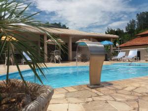 a pool with a water fountain next to a house at Pousada Encantos da Serra in Serra Negra