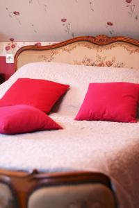 a bed with two red pillows on it at Les Renaudines in Château-Renault