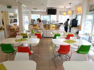 カールスルーエにあるホテル アヴィヴァの白いテーブルと緑の椅子が備わるレストラン
