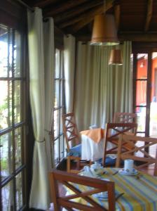 a dining room with a table and chairs and windows at Estalagem Capitão Gancho in Praia do Rosa