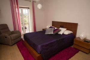 a bedroom with a bed and a chair and a window at Quinta da Pedra Grande in Monsanto