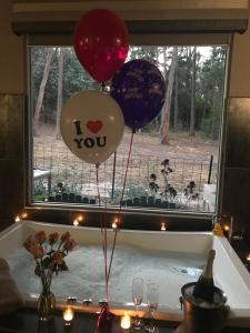 a group of balloons in a bath tub with a window at Spa Suites at RAVEN in Hepburn Springs