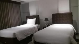 two beds in a hotel room with white sheets at Anshel Hotel Seminyak in Seminyak