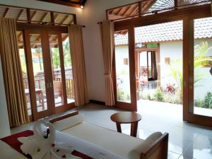 een woonkamer met een witte bank en glazen schuifdeuren bij Amaya Cottage Ubud by SHM in Ubud +37 foto's