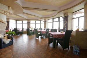 ein Esszimmer mit Tischen, Stühlen und Fenstern in der Unterkunft Casa Dacilor Liberi in Ranca