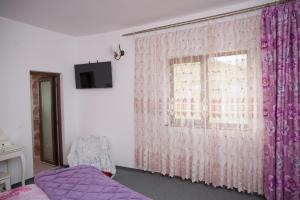 Zimmer mit einem Fenster mit einem lila Vorhang in der Unterkunft Casa Dacilor Liberi in Ranca
