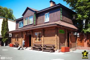 Ein Mann geht vor einem Holzhaus entlang in der Unterkunft HotelHola in Tschernihiw