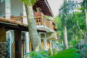 a house with a balcony and palm trees at Morning Star in Mirissa