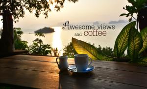 eine Tasse Kaffee auf einem Holztisch mit Blick auf das Wasser in der Unterkunft Tha Khao Bay View in Ko Yao Noi