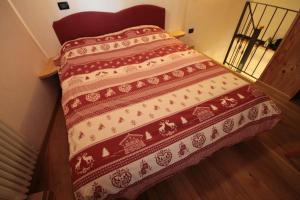 Una cama con colcha roja y blanca. en Appartamenti Peroulaz, en Charvensod