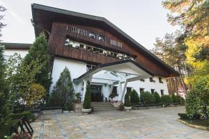 ein großes weißes Gebäude mit einem Holzdach in der Unterkunft Family hotel Borova Gora in Pirdop