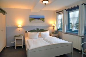 a bedroom with a white bed and two windows at Pension zum Brauhaus in Stralsund