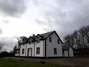 une maison blanche avec des fenêtres rouges sur un champ dans l'établissement Willowfarmhouse, à Milford
