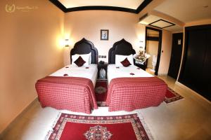 two beds in a room with a red rug at Hotel Imperial Plaza & Spa in Marrakech