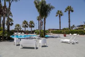 a group of chairs and a swimming pool with palm trees at Perla Hotel e Garden - Free Parking and Pool - Open area with Beautiful view of the Landscape in Capaccio-Paestum