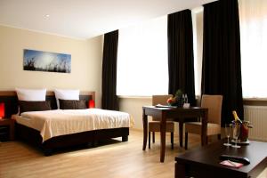 a bedroom with a bed and a table and a desk at home Hotel in Wilhelmshaven