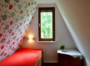 a bedroom with a red bed and a window at Finnhütte von Mai bis September in Wittenbeck