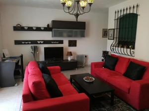 a living room with two red couches and a tv at Village Corner 3 bedroom apartment with Garage in Marsaskala