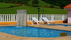 deux chaises et une fontaine dans une piscine dans l'établissement Chalé Recanto Monte Sinai, à Piracaia