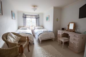 a bedroom with two beds and a dresser and a mirror at Court Barton Farm in Aveton Gifford