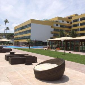 a resort with a large building with a large couch and a pool at Praia de Tabatinga- Flat do BZ - 2 quartos in Conde