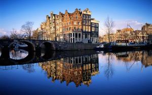 a bridge over a river with buildings and a city at Central & Quiet Canal Apartment in Amsterdam