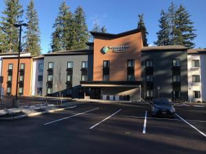a building with a car parked in a parking lot at WoodSpring Suites Seattle Redmond in Redmond