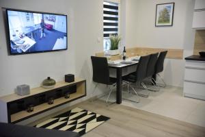 a dining room with a table and a tv on the wall at Apartamenty Platan Opieszyn in Września