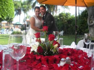 uma noiva e um noivo em pé em frente a uma mesa com rosas em Hotel & Spa Villa Vergel em Ixtapan de la Sal