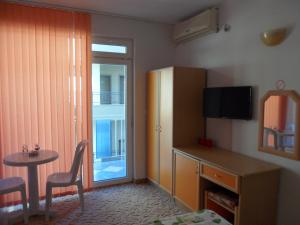 a small room with a table and a refrigerator and a table and chair at Sianie Guest House in Ravda