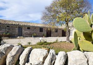 a house with a cactus and a stone fence at Agriturismo Tenuta Carbonara in Balata di Modica