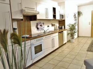 een keuken met witte kasten en een fornuis met oven bij Sterne-Ferienwohnung-Apartment Regnitztal in Buttenheim