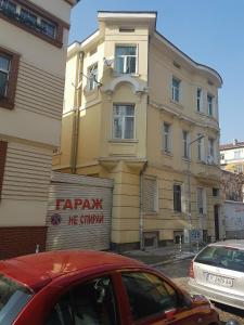 czerwony samochód zaparkowany przed budynkiem w obiekcie The Yellow House in Sofia w mieście Sofia