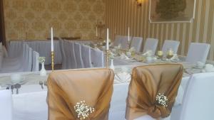 une grande table avec des tables blanches, des chaises et des bougies dans l'établissement Gasthaus Schillebold, à Peitz