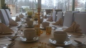 una mesa larga con platos, tazas y cubiertos en Gasthaus Schillebold, en Peitz
