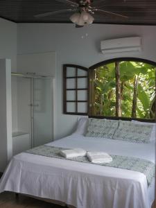 1 dormitorio con 1 cama blanca y ventana en Pousada Toca do Mar, en Praia de Palmas