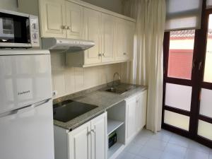 a kitchen with white cabinets and a sink and a microwave at Minipiso in Los Llanos de Aridane