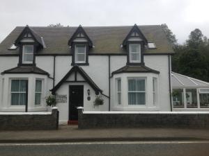 una casa blanca con techo negro en Craigbank Guest House en Crianlarich