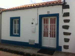 a white house with blue trim and a door at Casinha Azul in Horta
