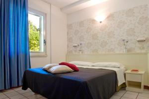 a bedroom with a bed with blue curtains and a window at Residenza Villa Lidia in Riccione +17 photos
