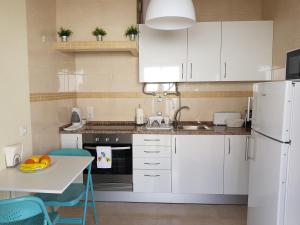La cuisine est équipée de placards blancs et d'un réfrigérateur blanc. dans l'établissement Páteo Badajoz, à Sintra