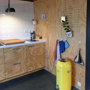 eine Küche mit Holzschränken und einem gelben Mülleimer in der Unterkunft Groeten uit Hoogmade - rural cottage in Hoogmaden