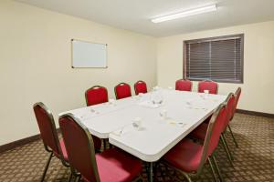 a conference room with a white table and red chairs at Days Inn by Wyndham Fort Dodge in Fort Dodge