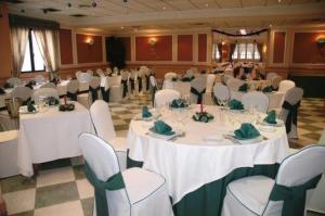 un salón de banquetes con mesas blancas y sillas blancas en Hotel Galaico, en Collado-Villalba
